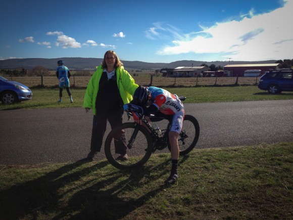 An exhausted Shannon Johnson is supported by commissaire Lisa Hocking just after Shannon won stage 1 in men's A grade.